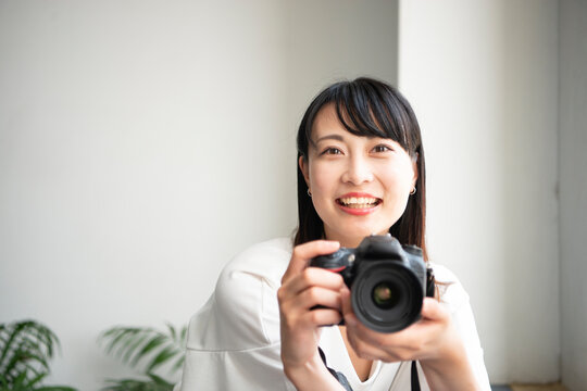 一眼レフカメラを構えて笑っている女性