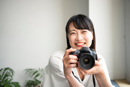 一眼レフカメラを構えて笑っている女性