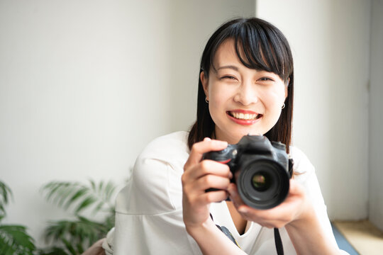 一眼レフカメラを構えて笑っている女性
