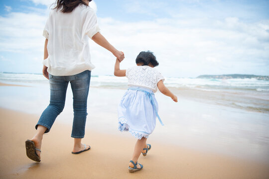 ビーチを歩いている親子の後ろ姿