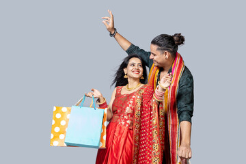 Happy indian couple wearing traditional cloths holding shopping bags and celebration diwali festival together
