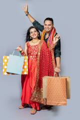 Happy indian couple wearing traditional cloths holding shopping bags and celebration diwali...