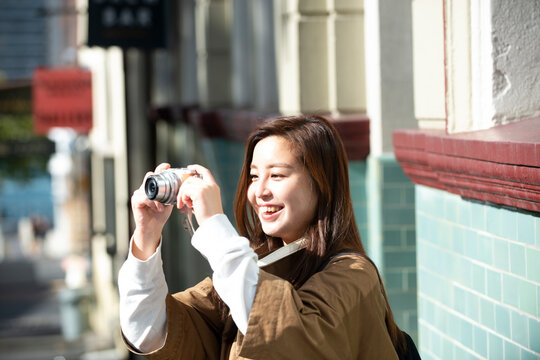 街でカメラを構えて笑っている女性