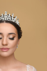 Beautiful young woman wearing luxurious tiara on beige background, space for text © New Africa