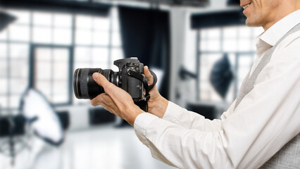 Closeup of smiling male photographer with professional camera working in photo studio, The...