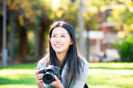 一眼レフのカメラを持って笑っている女性