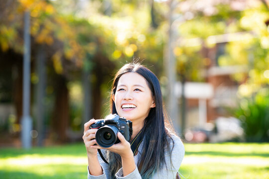 一眼レフのカメラを持って笑っている女性