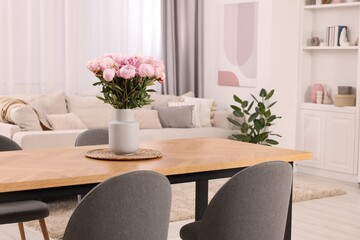 Table, chairs and vase with peonies in stylish dining room
