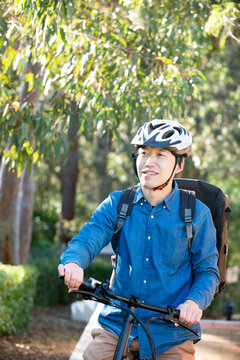 自転車に乗っているるフードデリバリー配達員男性