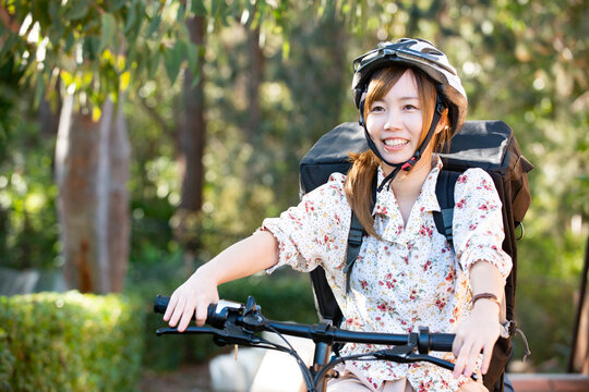 自転車に乗っているるフードデリバリー配達員女性