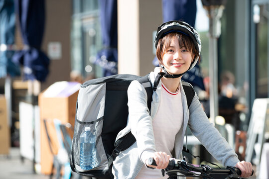 自転車に乗ったフードデリバリーの配達員の女性