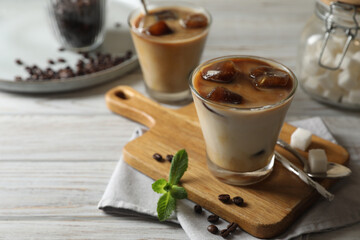 Delicious iced coffee with milk, beans and mint on white wooden table, space for text