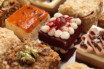 Pieces of different delicious cakes on table, closeup