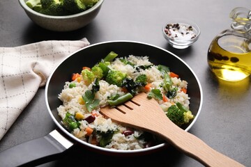 Tasty fried rice with vegetables served on black table, closeup