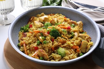 Tasty rice with meat and vegetables in frying pan on white table, closeup