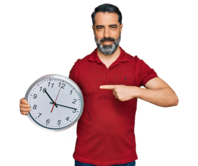 Middle aged man with beard holding big clock smiling happy pointing with hand and finger