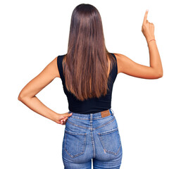 Young hispanic woman wearing casual clothes posing backwards pointing ahead with finger hand