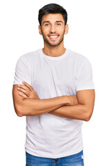 Young handsome man wearing casual white tshirt happy face smiling with crossed arms looking at the camera. positive person.