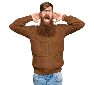 Young irish redhead man wearing casual clothes and glasses crazy and scared with hands on head, afraid and surprised of shock with open mouth