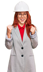 Young redhead woman wearing architect hardhat celebrating surprised and amazed for success with arms raised and open eyes. winner concept.