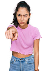 Hispanic teenager girl with dental braces wearing casual clothes pointing displeased and frustrated to the camera, angry and furious with you