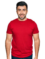 Fototapeta premium Hispanic man with beard wearing casual red t shirt with a happy and cool smile on face. lucky person.