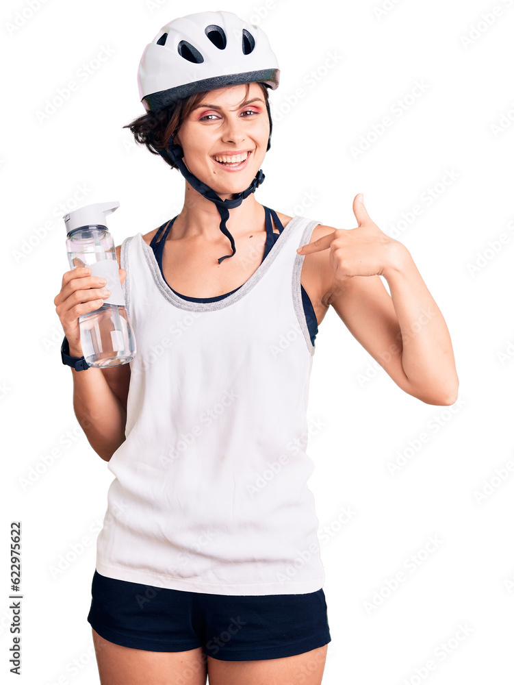 Poster Beautiful young woman with short hair wearing bike helmet and holding water bottle pointing finger to one self smiling happy and proud