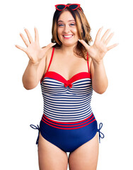 Young beautiful caucasian woman wearing swimwear showing and pointing up with fingers number ten while smiling confident and happy.