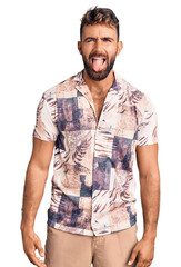 Fototapeta premium Young hispanic man wearing summer clothes sticking tongue out happy with funny expression. emotion concept.