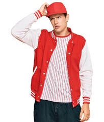 Handsome caucasian man wearing baseball uniform confuse and wonder about question. uncertain with doubt, thinking with hand on head. pensive concept.