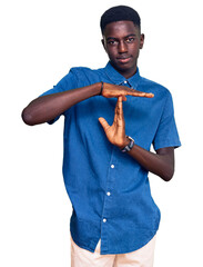 Young african american man wearing casual clothes doing time out gesture with hands, frustrated and...
