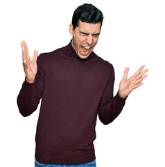 Handsome hispanic man wearing casual turtleneck sweater celebrating mad and crazy for success with arms raised and closed eyes screaming excited. winner concept