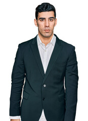 Handsome hispanic man wearing business clothes relaxed with serious expression on face. simple and natural looking at the camera.