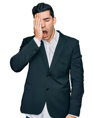 Handsome hispanic man wearing business clothes yawning tired covering half face, eye and mouth with hand. face hurts in pain.