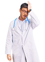Fototapeta premium Handsome young man with bear wearing doctor uniform surprised with hand on head for mistake, remember error. forgot, bad memory concept.
