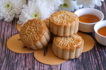 Obraz na płótnie Canvas Chinese Mid-Autumn Festival concept made from mooncakes, tea decorated with Chrysanthemum blossom on wooden background.