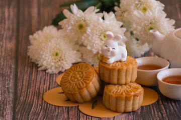 Fototapeta na wymiar Chinese Mid-Autumn Festival concept made from mooncakes, tea decorated with Chrysanthemum blossom and rabbit on wooden background.