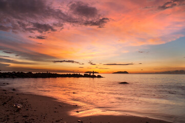 Beautiful beach with dramatic sunset sky and silhouette of few anglers