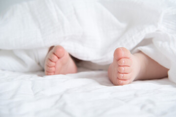 baby bare feet on a white bed with a white blanket