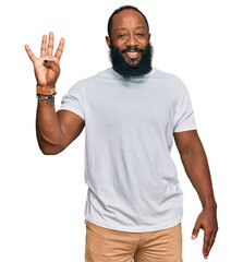 Young african american man wearing casual white tshirt showing and pointing up with fingers number four while smiling confident and happy.