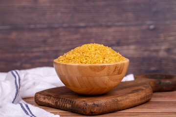 Bulgur on wood background. Bulgur wheat grains in wooden bowl