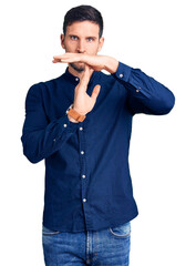 Young handsome man wearing casual shirt doing time out gesture with hands, frustrated and serious...