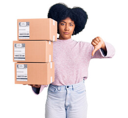 Young african american girl holding delivery package with angry face, negative sign showing dislike...