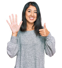 Beautiful asian young woman wearing casual clothes showing and pointing up with fingers number six while smiling confident and happy.