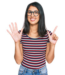 Beautiful asian young woman wearing casual clothes and glasses showing and pointing up with fingers number seven while smiling confident and happy.