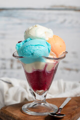 İce cream on wood background. Mixed ice cream balls in glass bowl. Cherry, lemon, caramel, chocolate and milk ice cream in a sundae dish. Close up