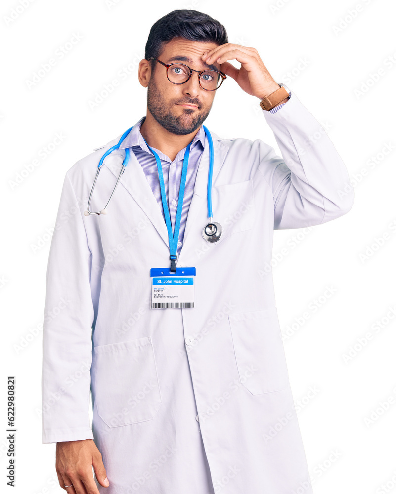 Wall mural Young hispanic man wearing doctor uniform and stethoscope worried and stressed about a problem with hand on forehead, nervous and anxious for crisis