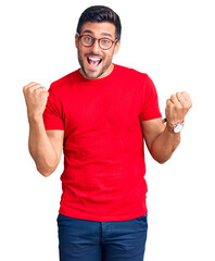 Young hispanic man wearing casual clothes and glasses screaming proud, celebrating victory and success very excited with raised arms