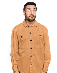 Young hispanic man wearing casual clothes smiling looking to the side and staring away thinking.