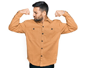 Young hispanic man wearing casual clothes showing arms muscles smiling proud. fitness concept.